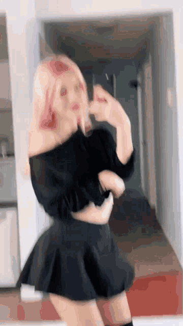 a woman with pink hair is taking a selfie in front of a mirror while wearing a black skirt .