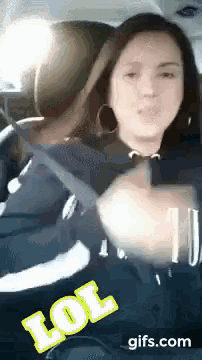 a woman sitting in a car with a lol gif above her