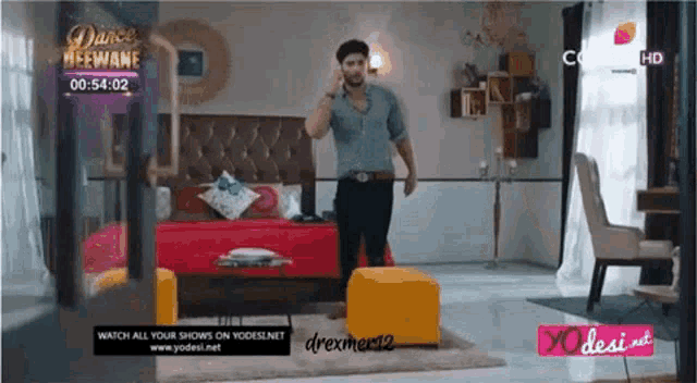 a man is standing in front of a bed in a bedroom talking on a phone .