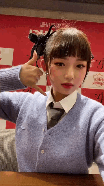 a girl in a blue sweater and tie giving a thumbs up sign