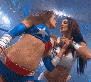 two women are wrestling in a ring and one of them is wearing a superhero outfit .