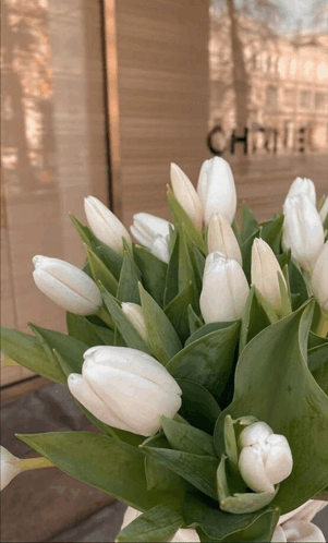 a bouquet of white flowers is in front of a chanel store