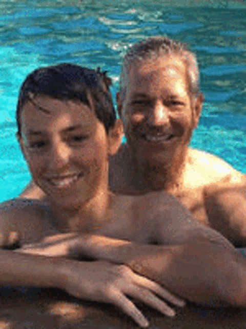 a man and a boy are sitting in a swimming pool .