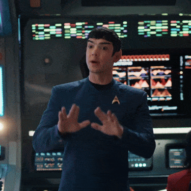 a man in a star trek uniform stands in front of a large screen that says ' discovery ' on it
