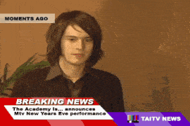 a young man is standing in front of a breaking news screen