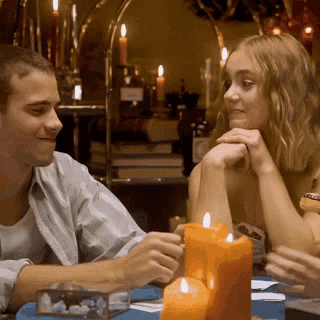 a man and a woman sit at a table with candles in front of them