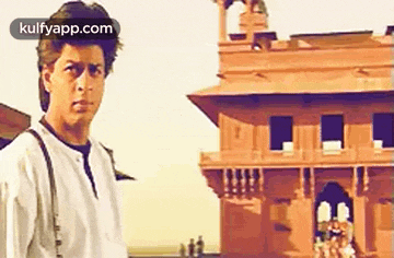 a man in a white shirt is standing in front of a red building .