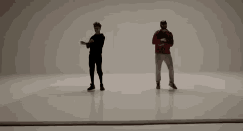 two men are standing next to each other on a white surface and dancing .