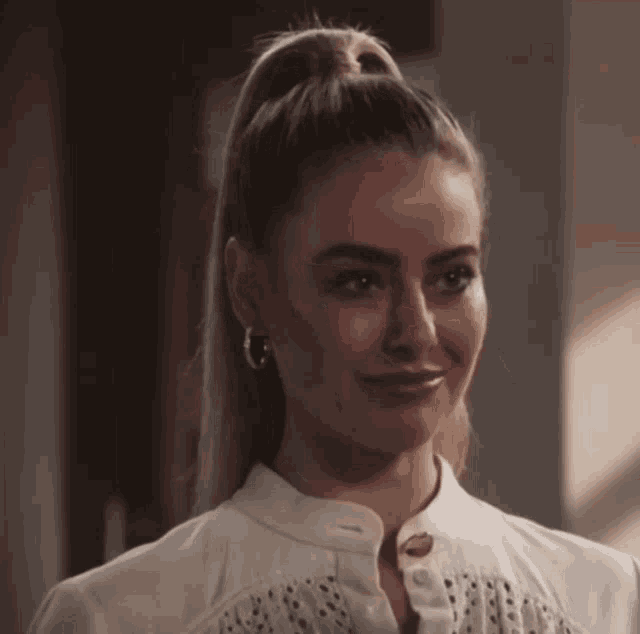 a woman with a ponytail is wearing hoop earrings