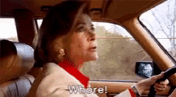 an elderly woman is driving a car and says whore .