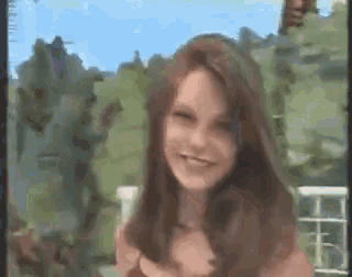 a woman with long brown hair is smiling in a blurry picture