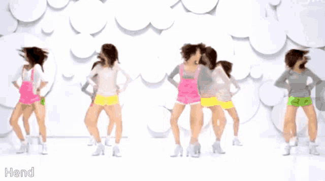a group of girls are dancing in front of a white wall with the word hend on the bottom right
