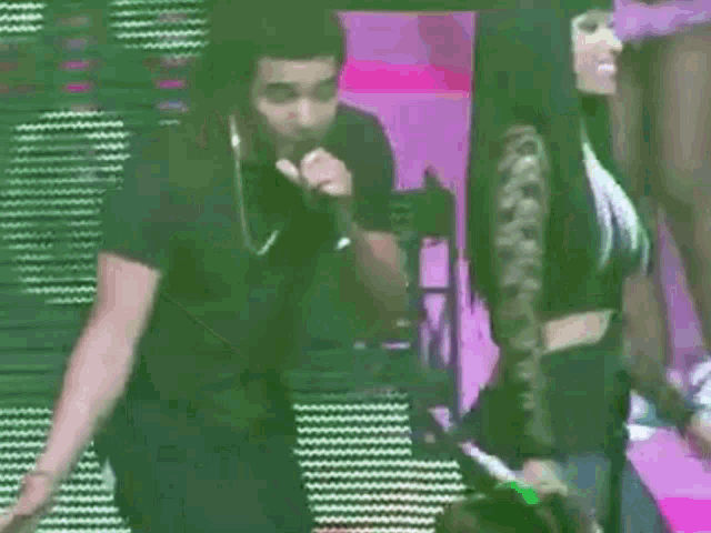 a man is singing into a microphone while a woman is standing behind him .