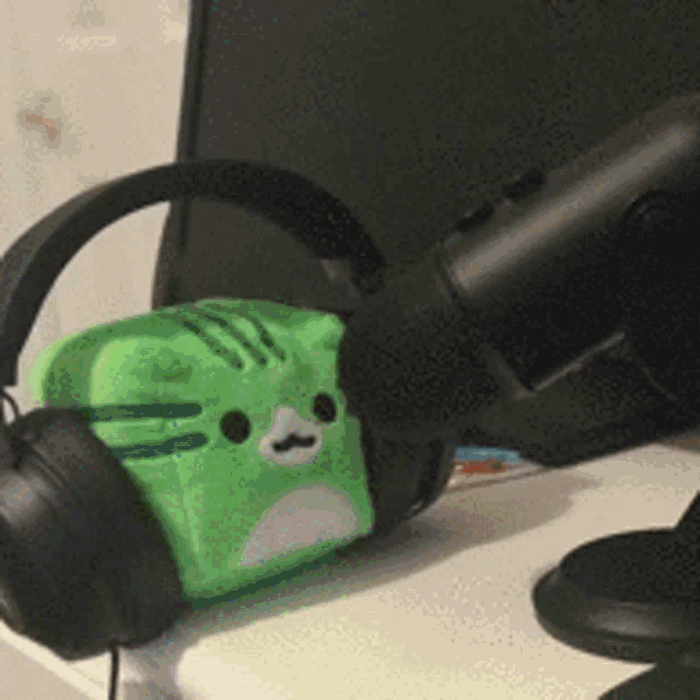 a pair of headphones sitting next to a green stuffed cat