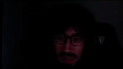 a close up of a person 's face with a black background and a red glow