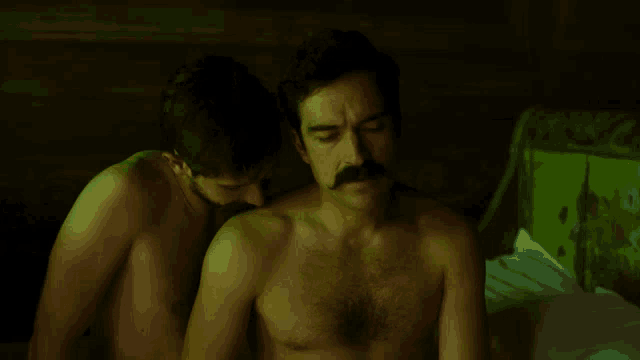 a man with a mustache is kissing another man 's neck