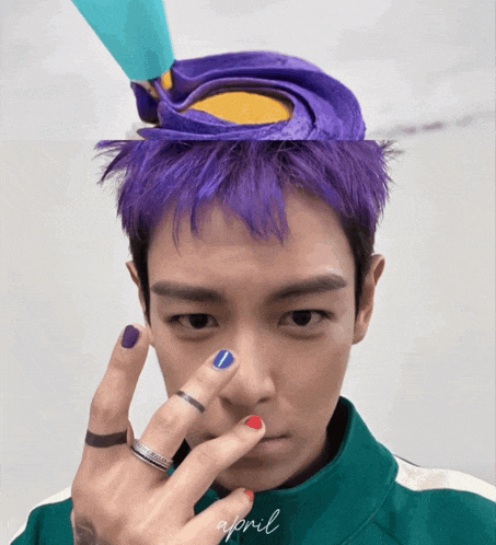 a man with purple hair is wearing a green jacket with april written on the bottom