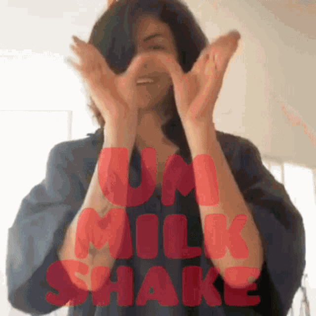 a woman is clapping her hands in front of a sign that says milkshake