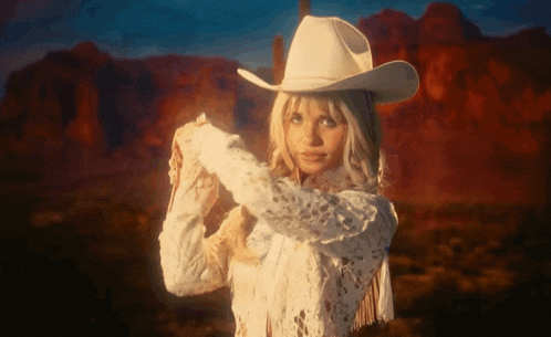 a woman wearing a white cowboy hat and a white lace top