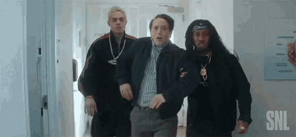 three men are walking down a hallway holding a man in their arms .