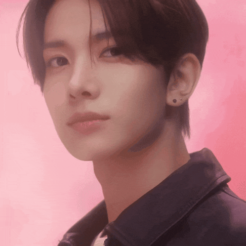 a close up of a young man 's face against a pink background