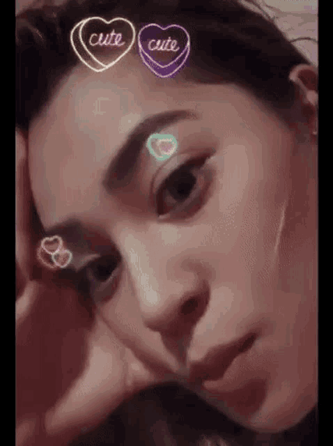 a close up of a woman with neon hearts on her face .