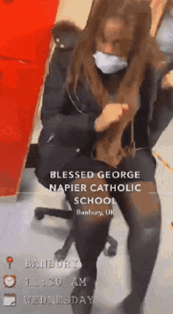 a woman wearing a mask is sitting in a chair at the blessed george napier catholic school in banbury uk