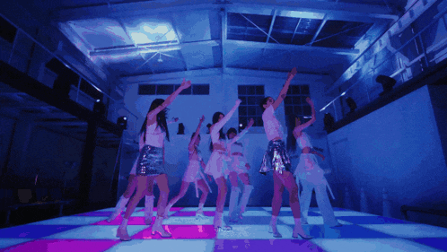 a group of women are dancing on a dance floor in a dark room