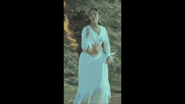 a woman in a white dress is dancing in front of a wall .