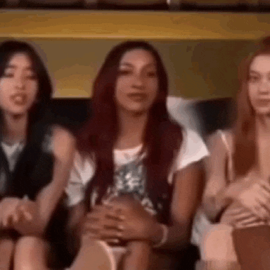 three women are sitting next to each other on a couch and talking to each other .