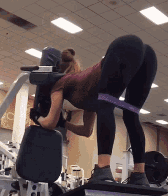 a woman is doing exercises on a machine with a purple band around her waist