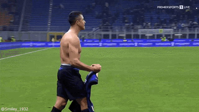 a shirtless man is walking on a soccer field in front of a screen that says premier sports live