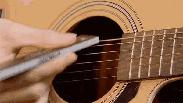 a person is playing an acoustic guitar with a pencil in their hand
