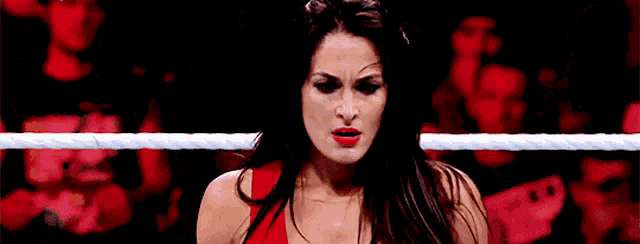 a woman in a red dress is standing in a wrestling ring looking at the camera .