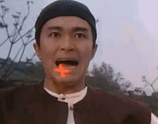 a man with a red cross on his tongue is making a funny face .