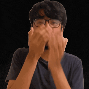 a man wearing glasses covers his face with his hands