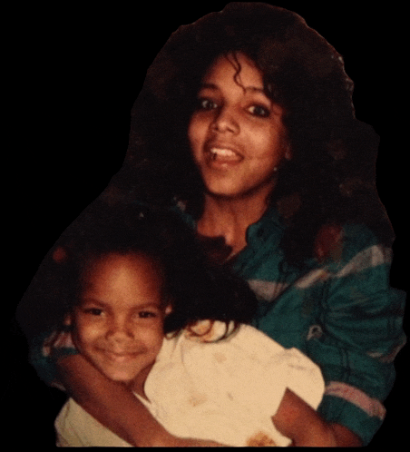 a woman is holding a little girl in her arms and the little girl is smiling