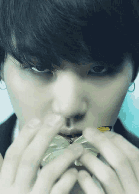 a close up of a person holding a butterfly in front of their mouth