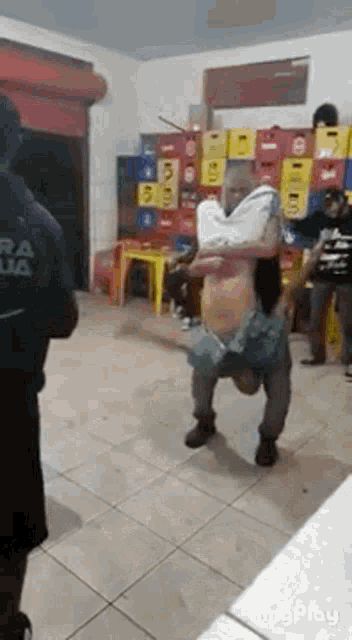 a man is carrying a woman on his shoulders in a room with a lot of crates .