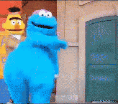 cookie monster and bert from sesame street are standing next to each other in front of a building .