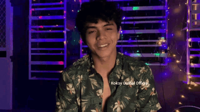 a young man wearing a green shirt with the words kokoy @ global official on the bottom right