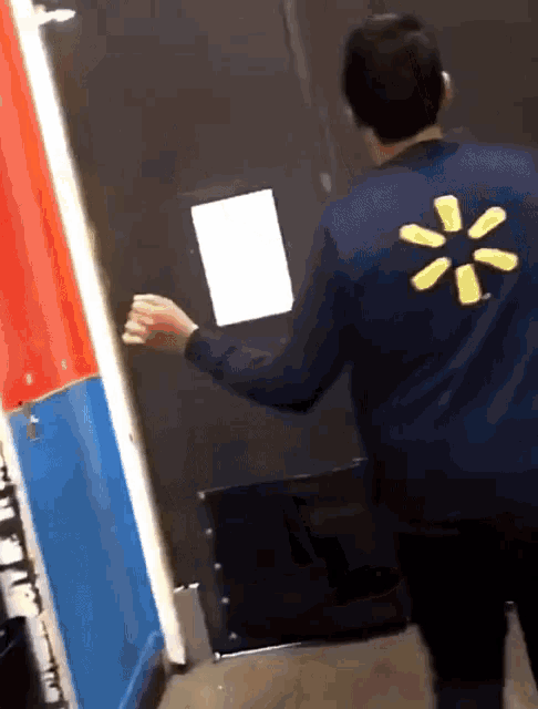 a man with a walmart logo on his back stands in front of a door