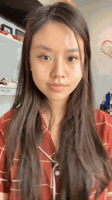 a woman with long hair is wearing a plaid shirt