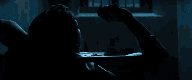 a person is laying in a dark room with a window in the background