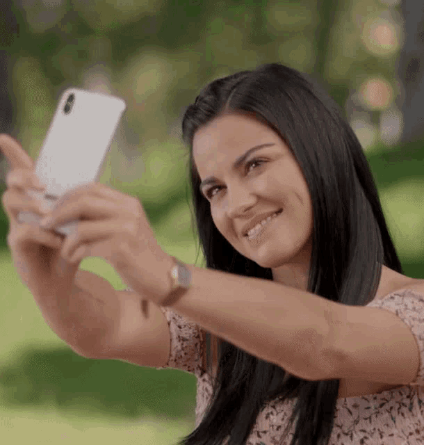 a woman taking a selfie with her phone in a park