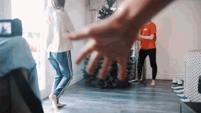 a person 's hand is reaching for a christmas tree in a living room