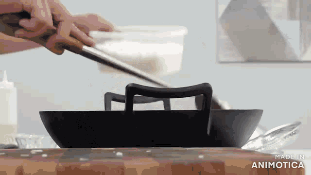a person is cooking food in a wok on a cutting board with a spatula .