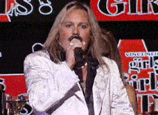 a man singing into a microphone in front of a sign that says ' girls '