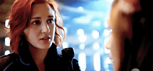 a woman with red hair is looking at another woman in a dark room .