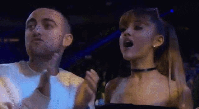 a man and a woman are standing next to each other and clapping .